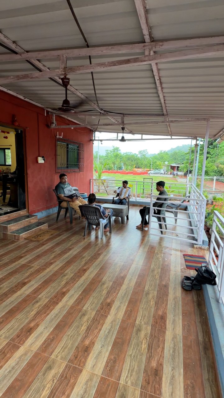 Spacious wooden-floored sitting porch of Nirvi Farms farmhouse